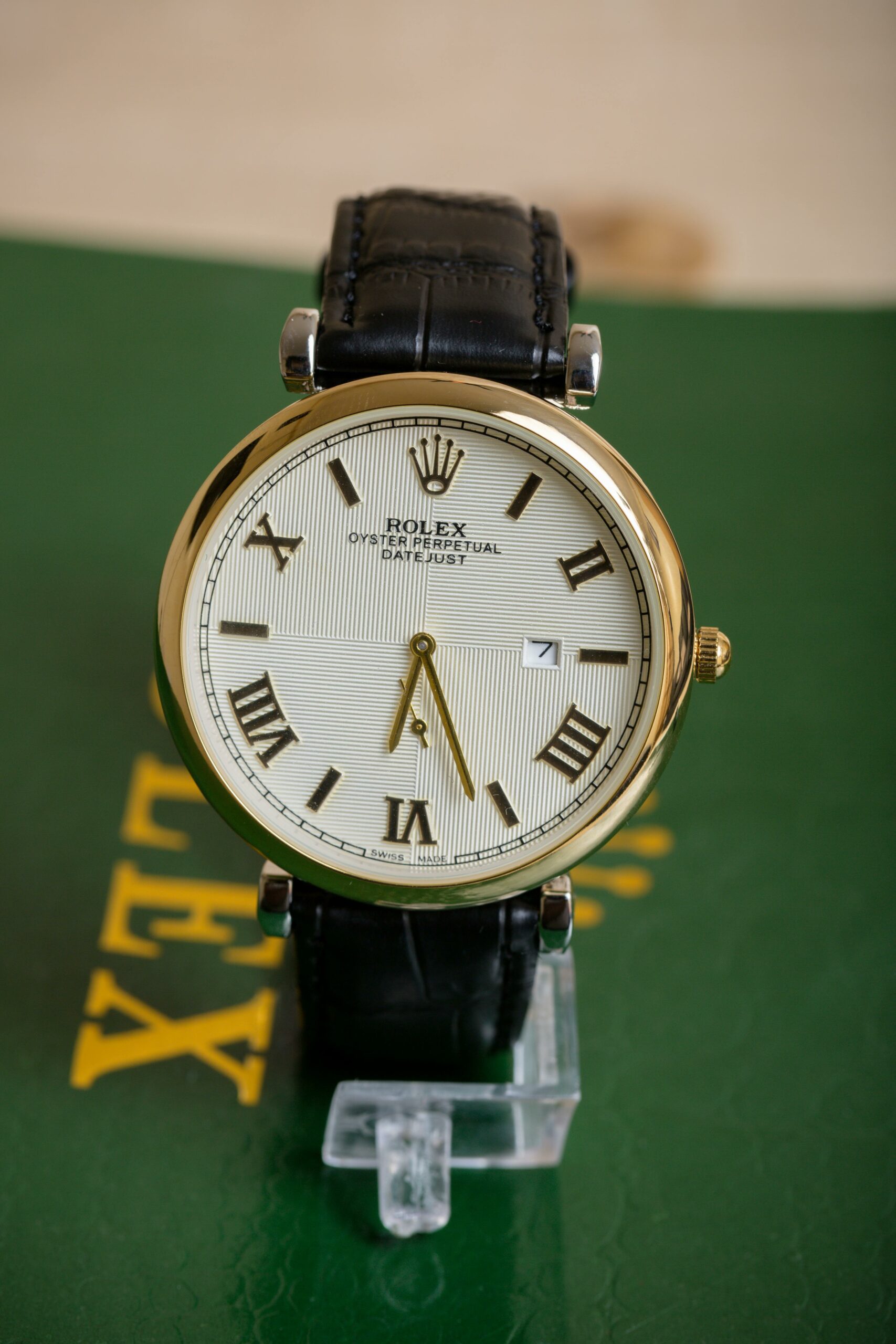 A gold Rolex Oyster Perpetual Datejust watch with a white dial, Roman numerals, and a black leather strap.