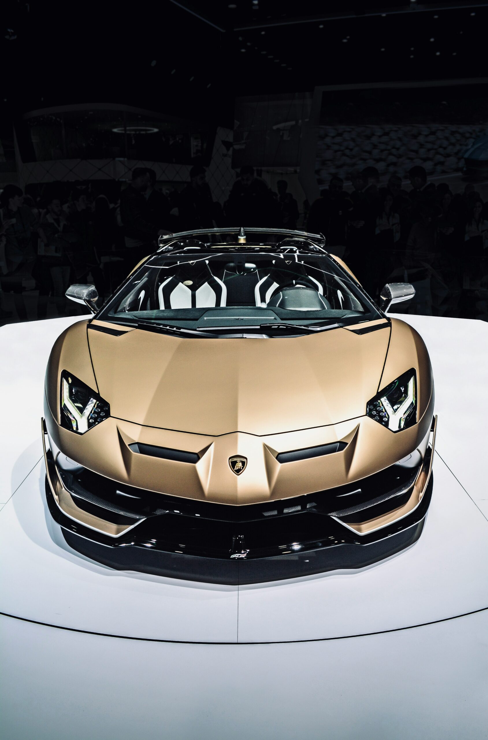 A gold Lamborghini Aventador SVJ Roadster on display, front view.