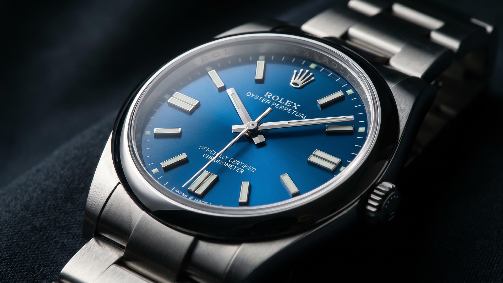 Close-up of a Rolex Oyster Perpetual watch with a blue sunburst dial and silver indices.