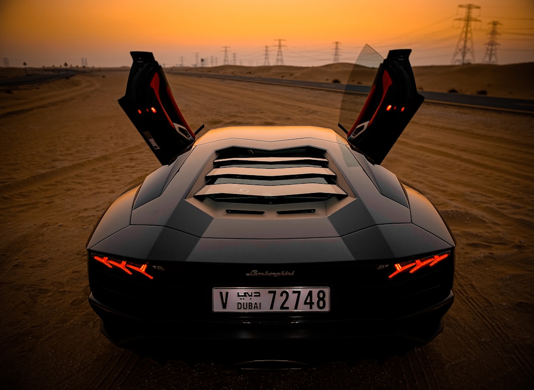 Lamborghini with gull-wing doors open on a desert road at sunset, dubai license plate visible on the rear.
