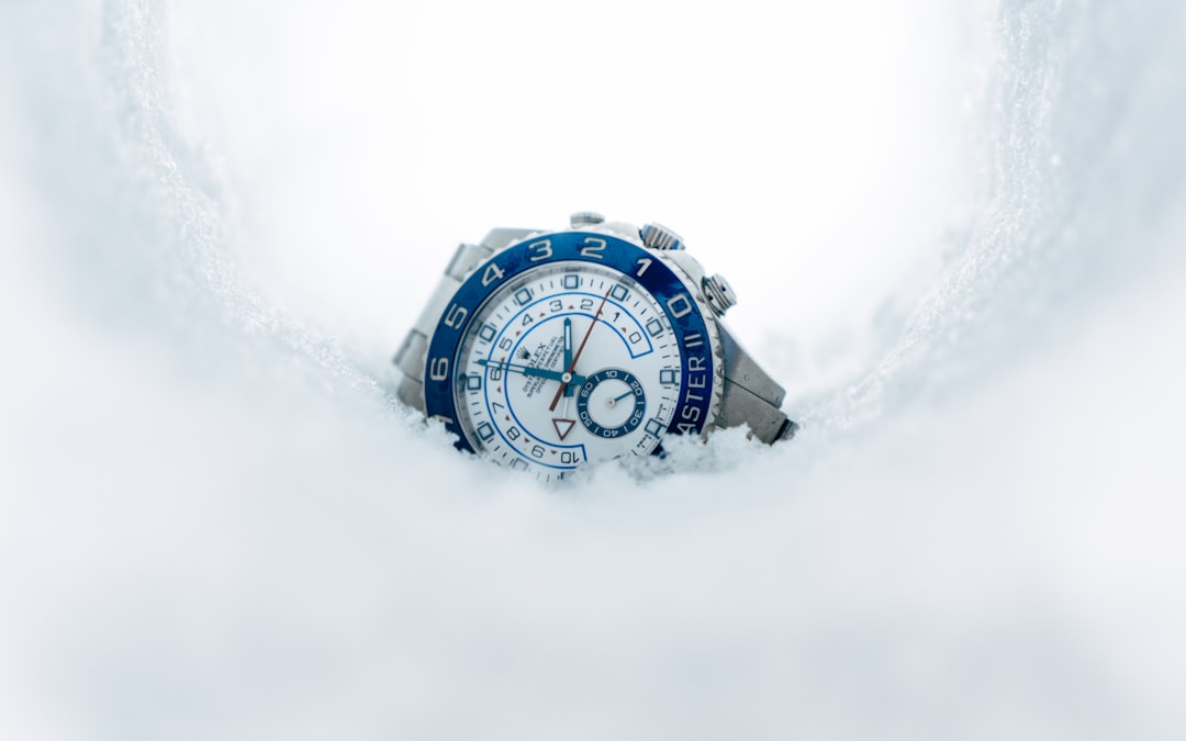 Get-a-loan-with-your-rolex-collateral-lending-guide - borro Wristwatch with a blue bezel partially buried in white snow, silver band visible