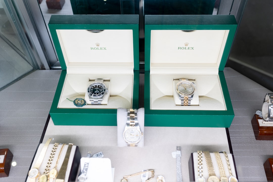 Two rolex watches on display in green boxes, with additional jewelry laid out in front in a showroom case.
