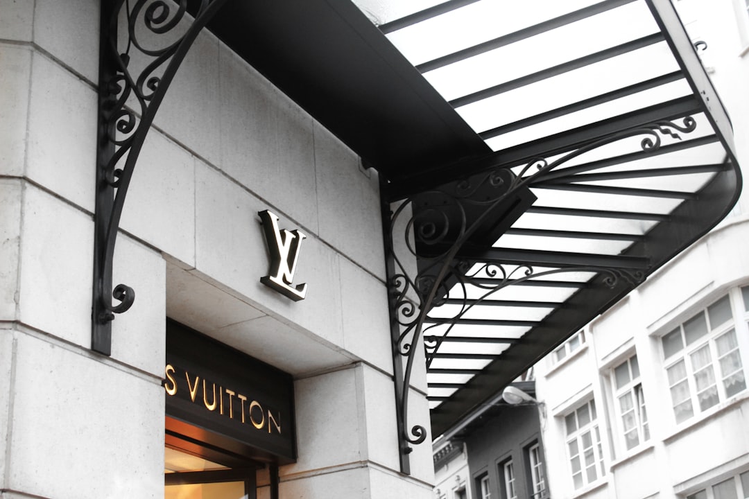 Louis vuitton storefront with illuminated lv logo above the entrance and a decorative black iron canopy.