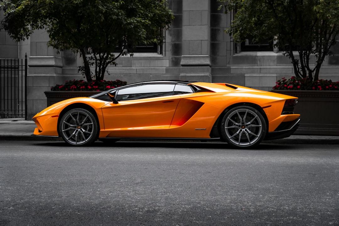 Lamborghini-pop-culture-impact-design-psychology - borro - borro Orange lamborghini aventador parked on an urban street, gray stone buildings and trees in the background.