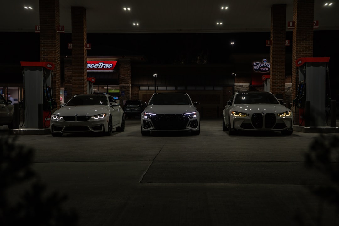 Three cars parked side by side under a gas station canopy at night, facing the camera (front view).