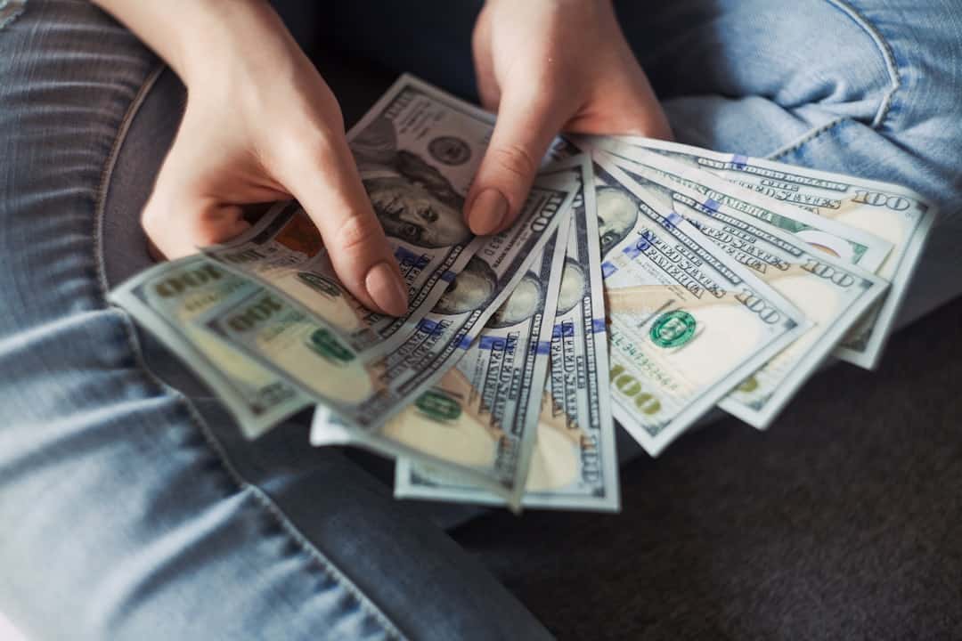 Person holding a fan of US dollar bills, focusing on cash and financial assets.