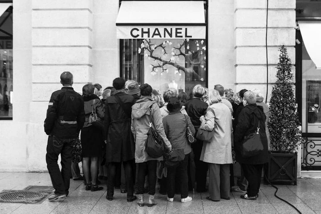 Crowd of people gathered outside a Chanel store on a city street.