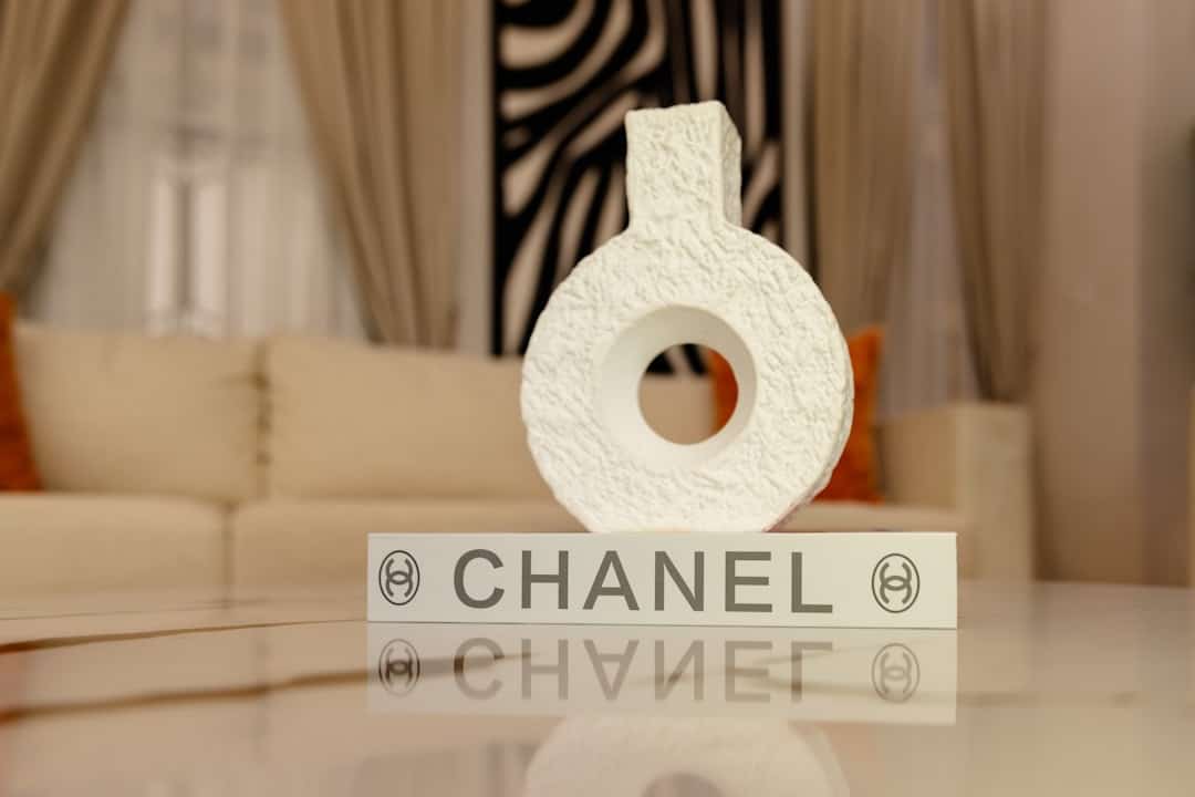 Elegant jewelry display featuring a Chanel box and a textured ring on a reflective surface.