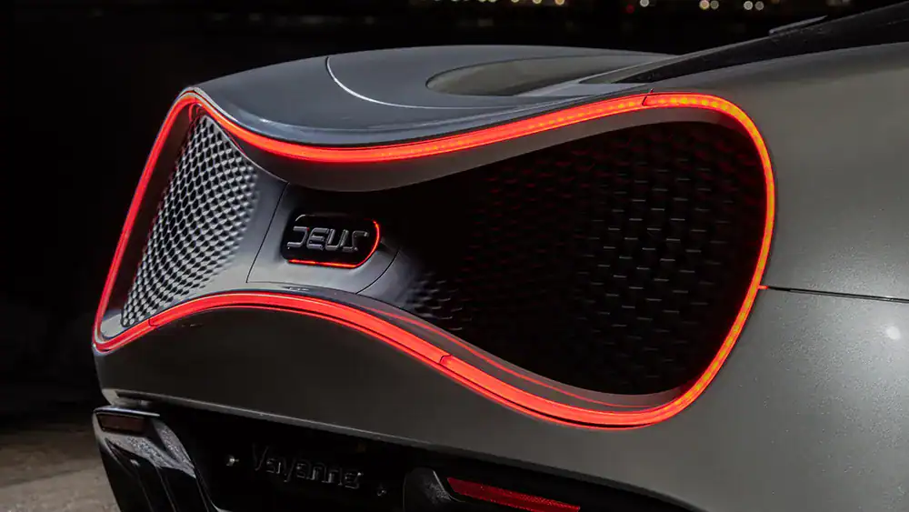 Close-up of a luxury car's front with LED accents and carbon fiber details.