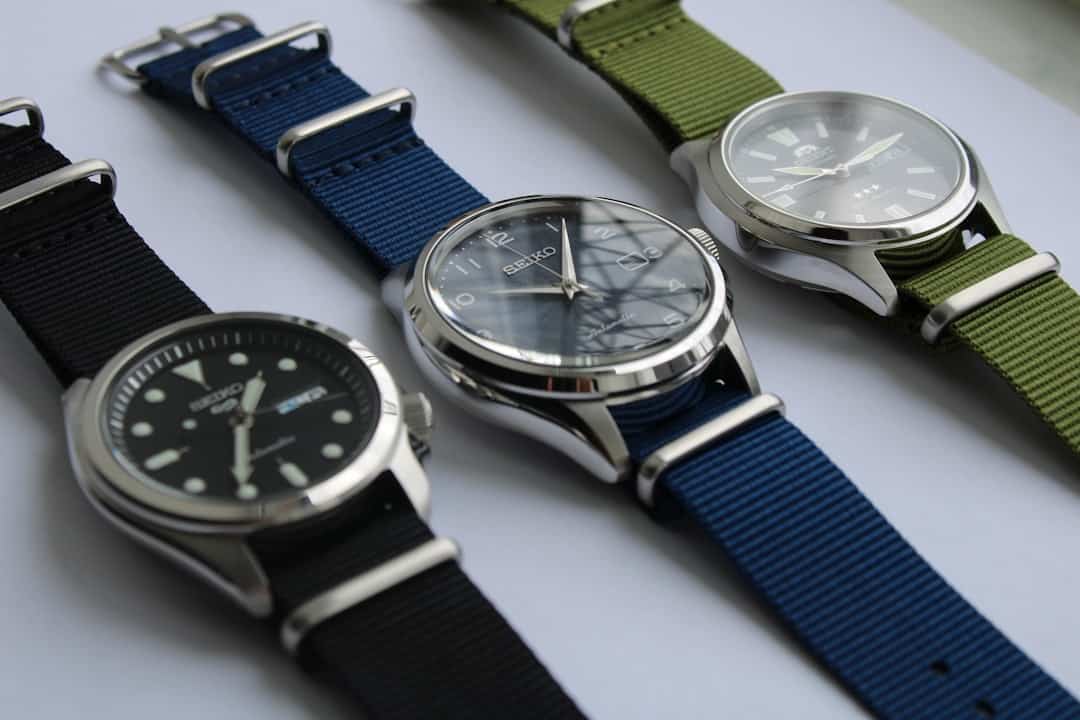 Three wristwatches with different colored straps on a white surface.
